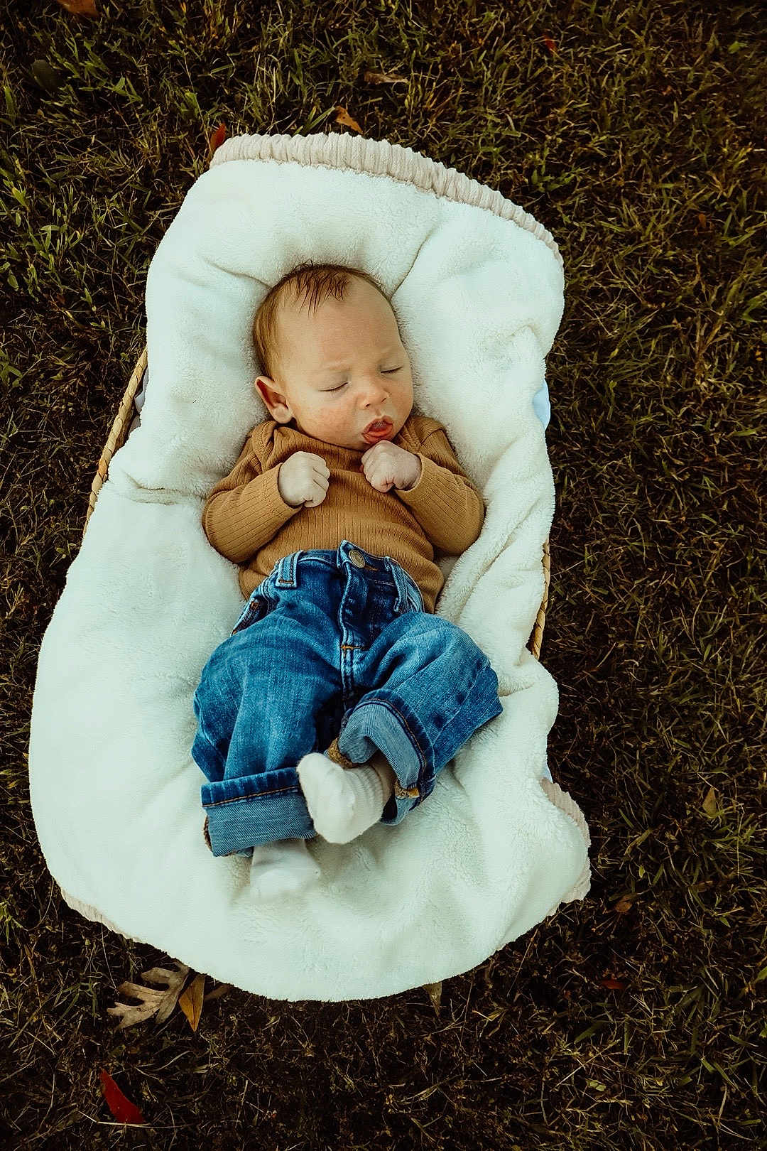 Jeremiah is registered to the contest to win money with this photo: baby, infant, sleeping, blanket, grass, outdoor, jeans, brown_sweater, cozy, cute, peaceful, child, nature, resting, casual_clothing, small_hands, white_socks, fall_leaves, relaxation, portrait