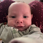 Jeremiah is registered to the contest to win money with this photo: baby, infant, face, close_up, selfie, child, expression, cozy, clothing, maroon, pattern, soft, cute, person, young, indoors, portrait, reaching, curious, skin