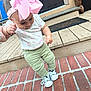 Felicity is registered to the contest to win money with this photo: baby, brick_porch, child, curious, cute, door, floral_shirt, footwear, green_pants, hand_holding, headband, infant, outdoor, person, pink_bow, sneakers, standing, support, toddler, wooden_steps