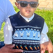 Carlos joined the competition — help win amazing prizes! child, boy, sunglasses, sweater_vest, bunny_pattern, carrot_pattern, short_sleeve_shirt, khaki_pants, adult_hand, outdoor, grass, sunlight, shadow, garden_pot, greenery, casual_clothing, portrait, person, daylight, fashion