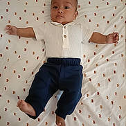 Charles participe au concours pour gagner de l'argent avec cette photo : baby, infant, child, lying_down, white_shirt, navy_pants, bed_sheet, pattern, cute, spread_eagle, calm_expression, indoor, person, face, feet, hands, looking, young, wearing_clothes, head