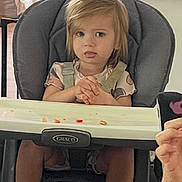 Hannah is registered to the contest to win money with this photo: toddler, child, high_chair, indoor, kitchen, food, seat, face, expression, hands, hair, clothing, table, foot, furniture, person, domestic, baby, appliance, curious