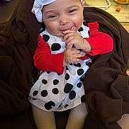 Rachael is registered to the contest to win money with this photo: baby, baby_rocker, blanket, bow, brown_blanket, child, couch, cozy, face, hands, happy, headband, indoor, infant, polka_dot_dress, portrait, red_sweater, sitting, smiling, toy
