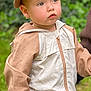 toddler, child, cap, jacket, outdoor, greenery, hand, person, face, blue_eyes, curious, clothing, young_child, casual_wear, nature, portrait, holding_hand, expression, hat, blurred_background