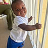 toddler, child, smiling, white_tshirt, blue_shorts, white_shoes, railing, handrail, indoors, person, cute, baby, portrait, happy, young_child, standing, human, skin, hair, floor