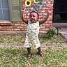 Brexton is registered to the contest to win money with this photo: arms_raised, baby, brick_wall, child, daytime, door, footwear, grass, greenery, happy, outdoor, person, plant, romper, sandals, smiling, summer, sunflowers, toddler, window