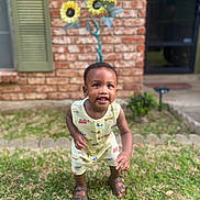 Brexton joined the competition — help win amazing prizes! baby, brick_wall, child, curious_expression, daylight, door, garden, grass, greenery, outdoor, person, playful, romper, sandals, standing, summer, sunflower_art, toddler, window, yellow_clothing