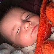 Deliah joined the competition — help win amazing prizes! baby, sleeping, infant, portrait, face, closed_eyes, blanket, orange_blanket, bundled, cozy, indoors, nap, peaceful, close_up, head, soft_lighting, pajamas, newborn, resting, cuddled