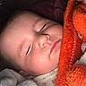 baby, blanket, bundled, close_up, closed_eyes, cozy, cuddled, face, head, indoors, infant, nap, newborn, orange_blanket, pajamas, peaceful, portrait, resting, sleeping, soft_lighting