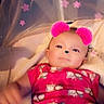 baby, infant, pink_clothing, animal_print, blanket, filter, pom_pom_ears, face, lying_down, stars, cute, soft_lighting, indoors, child, portrait, smile, hand, cozy, playful, adorable