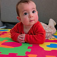 Gabrielle participe au concours pour gagner de l'argent avec cette photo : baby, child, red_sweater, colorful_mat, puzzle_mat, floor_play, curious_expression, rosy_cheeks, big_eyes, long_eyelashes, floral_skirt, white_socks, indoors, soft_lighting, portrait, closeup, infant, hands_folded, cute, playtime