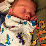 Halton joined the competition — help win amazing prizes! newborn, baby, sleeping, swaddled, blanket, colorful, hand, face, infant, closeup, tshirt, person, rest, peaceful, indoor, portrait, soft_light, skin, cute, cozy
