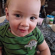 Jensen joined the competition — help win amazing prizes! toddler, child, baby, green_shirt, striped_shirt, dinosaur_patch, red_hair, blue_eyes, indoor, blanket, baby_items, smiling, cute, portrait, seated, young_child, face, person, casual_clothing, home