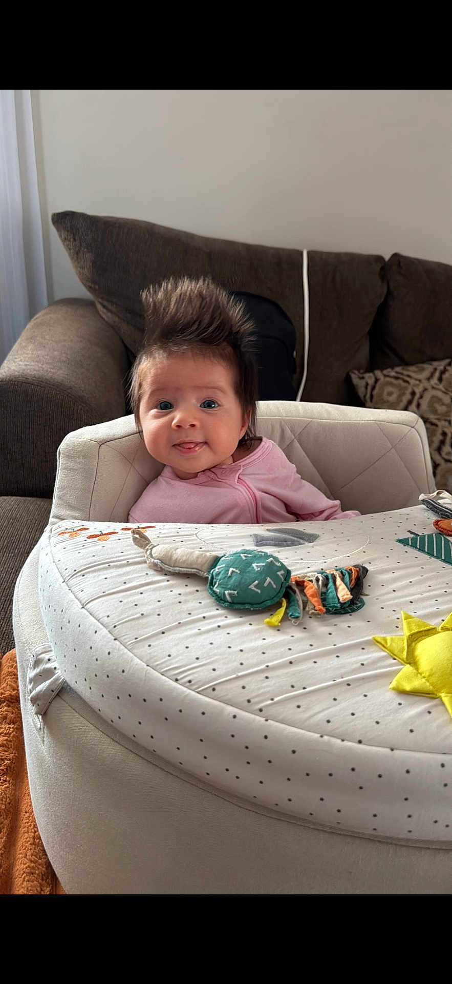 Rosalia joined the competition — help win amazing prizes! baby, infant, child, spiky_hair, tongue_out, baby_seat, play_mat, couch, cushion, living_room, cozy, patterned, soft_furniture, pink_clothing, cute, happy, portrait, indoor, person, smiling