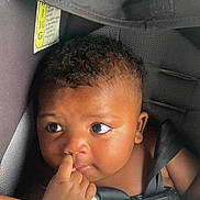 Jamius is registered to the contest to win money with this photo: baby, blanket, car_safety, car_seat, child, closeup, curious, cute, expression, face, finger, hand, indoors, infant, person, portrait, seatbelt, skin, strapped, young_child