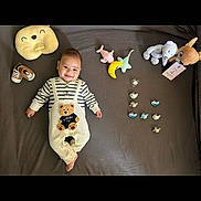 Alpcan a rejoint le concours — aidez-le/la à gagner de superbes lots ! baby, infant, smile, toy, plush_toy, pacifier, bed, blanket, clothing, footwear, cute, child, lying_down, striped_shirt, bear_design, stuffed_animal, soft_toy, indoor, happy, small_shoes