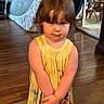 carpet, casual_clothing, child, curtains, cute, expression, flooring, furniture, hands_clasped, home, indoor, person, portrait, room, short_hair, standing, toddler, wooden_floor, yellow_dress, young_child
