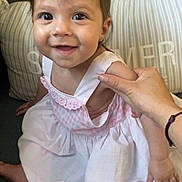 Sophia a rejoint le concours — aidez-le/la à gagner de superbes lots ! baby, child, smiling, dress, pink, white, arm, hand, couch, cushion, indoors, living_room, person, happy, sitting, face, head, hair, skin, human