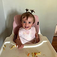 Bonnie is registered to the contest to win money with this photo: toddler, child, high_chair, bib, food, snack, smile, happy, indoor, pigtails, hair, face, person, baby_food, plastic, tray, feeding, cute, messy, eating