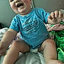 baby, child, smiling, blue_shirt, diaper, bed, blanket, indoor, happy, reaching, skin, face, person, young_child, cute, expression, infant, sitting, comfort, clothing