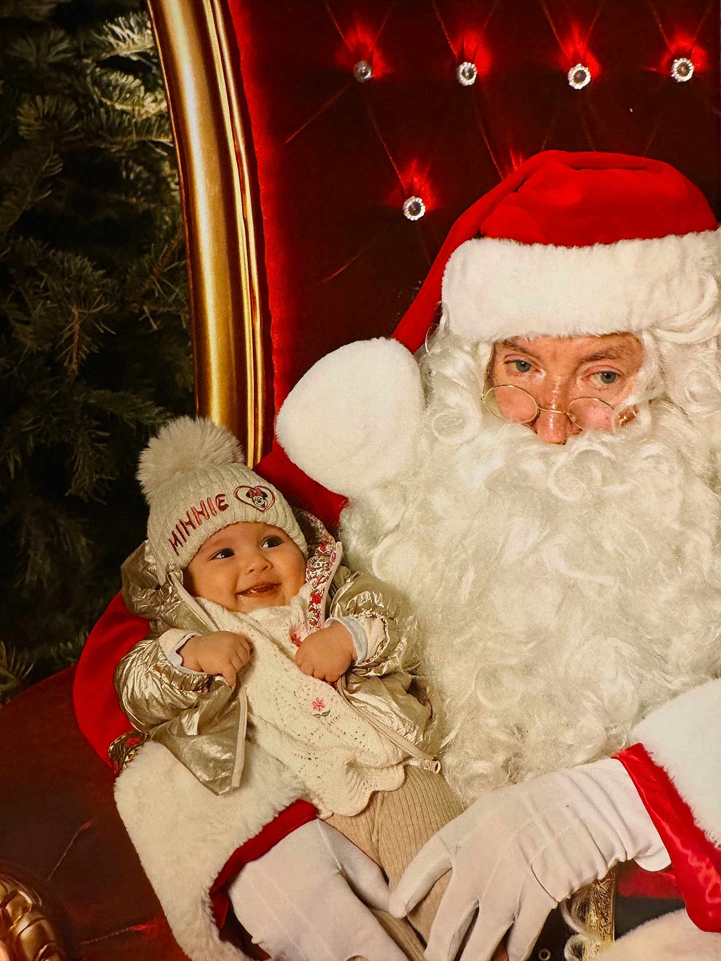 Séréna participe au concours pour gagner de l'argent avec cette photo : baby, child, santa_claus, christmas, holiday, hat, beard, glasses, red_clothing, white_gloves, chair, smile, festive, winter_clothing, tree, cozy, portrait, indoor, happy, person