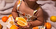 Mazikeen is registered to the contest to win money with this photo: child, toddler, smiling, grinning, portrait, sitting, indoor, bed, blanket, orange, citrus, lemon, fruit, sliced_orange, dress, floral_dress, barefoot, happy, warm_lighting, playful