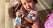 Mazikeen is registered to the contest to win money with this photo: backpack, child, colorful_clothing, curly_hair, doll, family, girl, hair_bows, hugging, indoor, living_room, orange_shoes, playtime, portrait, sitting, smiling, sofa, toddler, toy, wood_floor