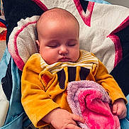 Nélya participe au concours pour gagner de l'argent avec cette photo : baby, sleeping, blanket, yellow_clothing, hand, face, head, cushion, seat, indoor, towel, soft_texture, peaceful, child, infant, closeup, portrait, comfort, relaxation, cute