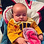 baby, sleeping, blanket, yellow_clothing, hand, face, head, cushion, seat, indoor, towel, soft_texture, peaceful, child, infant, closeup, portrait, comfort, relaxation, cute