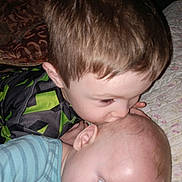 Furious is registered to the contest to win money with this photo: baby, child, kiss, bed, blanket, quilt, red_eye, face, person, infant, sibling, love, indoor, clothing, striped_shirt, green_shirt, hair, skin, closeup, tenderness