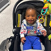 Alakai joined the competition — help win amazing prizes! baby, smiling, stroller, toy, hoodie, blue_pants, indoor, child, happy, infant, face, clothing, seat, person, playful, cute, young_child, casual, portrait, dangle