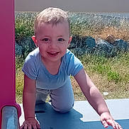 Estebann participe au concours pour gagner de l'argent avec cette photo : child, toddler, smiling, climbing, playground, slide, outdoor, grass, rocks, sunlight, happy, blue_shirt, pants, short_hair, crawling, daylight, shadow, nature, play, fun