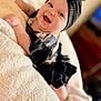 baby, beanie, blanket, bodypart, bonnet, cap, clothing, couch, face, finger, furniture, hand, happy, hat, head, newborn, person, photography, portrait, smile