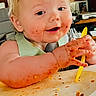 baby, high_chair, messy_face, spaghetti_sauce, yellow_spoon, food, happy, child, indoor, wooden_wall, table, feeding, smile, cute, infant, person, meal_time, face, hands, home