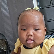 Jilisha is registered to the contest to win money with this photo: baby, bow, butterfly, child, closeup, curtain, cute, expression, face, fan, furniture, hand, head, holding, indoor, infant, person, skin, tongue_out, yellow_clothing