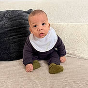 Elhan a rejoint le concours — aidez-le/la à gagner de superbes lots ! baby, infant, child, bib, couch, pillow, blanket, socks, sitting, portrait, indoor, cute, wide_eyes, hands, face, clothing, sofa, expression, cozy, home