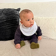 Elhan a rejoint le concours — aidez-le/la à gagner de superbes lots ! baby, bib, blanket, clothing, couch, curious, cute, face, feet, green_socks, hand, indoor, infant, looking_right, pillow, portrait, sitting, socks, soft_texture, young_child