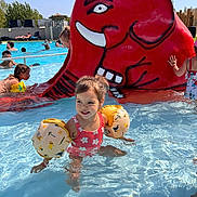 Manelle a rejoint le concours — aidez-le/la à gagner de superbes lots ! child, pool, water, swimsuit, floaties, red_elephant_slide, summer, outdoor, sunny, smiling, playing, family, fun, recreation, leisure, children, splashing, swimming_pool, people, daylight