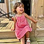 child, girl, smiling, red_dress, checkered_pattern, wooden_steps, outdoor, sunlight, summer, sandals, wooden_post, happy, cute, portrait, daylight, casual_clothing, young_child, playful, sitting, natural_light