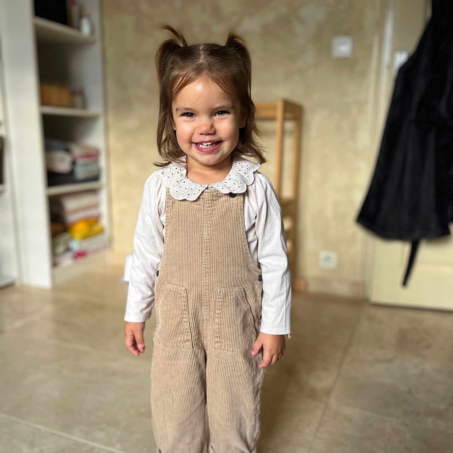 Manelle a rejoint le concours — aidez-le/la à gagner de superbes lots ! child, coat, corduroy_overalls, cute, door, fashion, floor_tiles, girl, hair_tied, happy, home, indoor, long_sleeve_shirt, person, playful, portrait, shelf, smiling, standing, striped_shoes