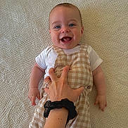 Malo a rejoint le concours — aidez-le/la à gagner de superbes lots ! baby, smiling, laughing, child, hand, tickling, overalls, white_shirt, blanket, textured, indoor, cute, happy, playful, infant, skin, person, scrunchie, ring, comfort