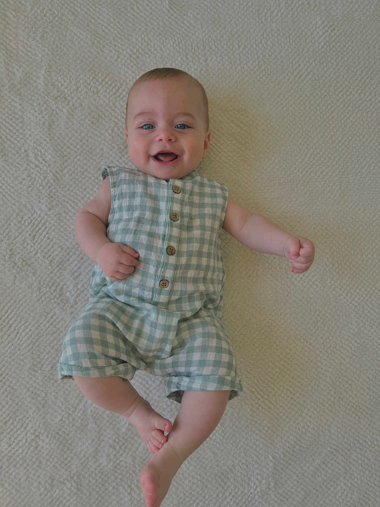 Malo a rejoint le concours — aidez-le/la à gagner de superbes lots ! baby, infant, smiling, lying_down, romper, checkered_clothing, blue_eyes, barefoot, cute, happy, child, skin, texture, blanket, buttoned, casual_wear, one_person, indoors, portrait, young_child