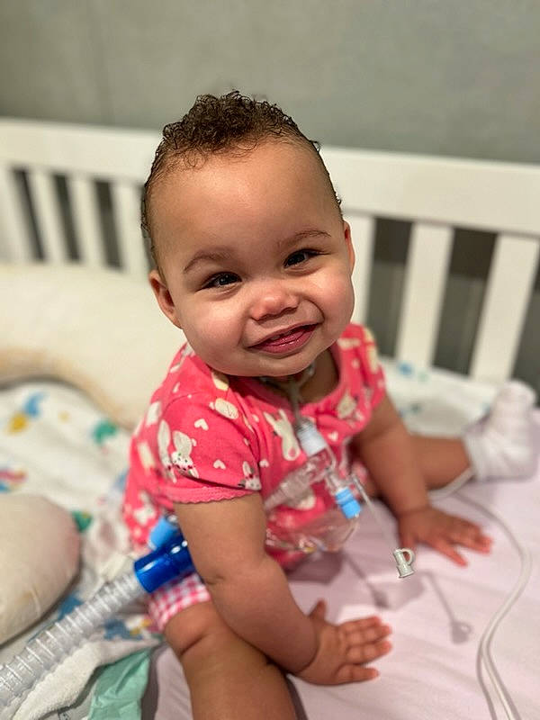 Paris is registered to the contest to win money with this photo: baby, baby_toddler_clothing, cheek, child, chin, event, eye, face, facial_expression, fun, hand, happy, iris, joy, mouth, nose, person, sitting, skin, smile