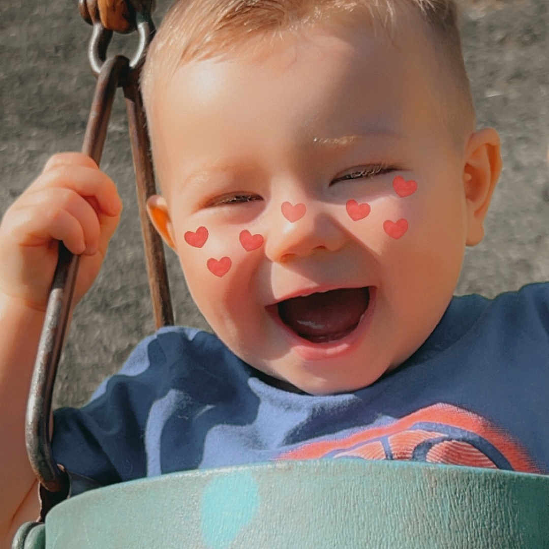Axton is registered to the contest to win money with this photo: baby, bodypart, clothing, face, grass, happy, head, laughing, mouth, outdoorplayarea, outdoors, person, photography, plant, playarea, portrait, smile, swing, teeth, toy