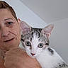person, cat, indoor, close_up, face, animal, pet, holding, white, gray, tabby, looking, curious, portrait, skin, short_hair, ear, nose, eye, hand