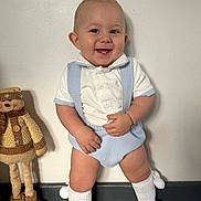 Dalton joined the competition — help win amazing prizes! baby, child, smile, standing, blue_outfit, white_shirt, knee_socks, shoes, stuffed_toy, doll, wooden_floor, wall, bracelet, happy, indoors, cute, playful, person, portrait, fashion