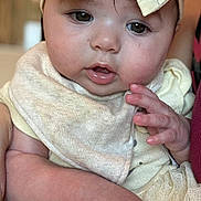 Paisley is registered to the contest to win money with this photo: baby, child, face, headband, yellow_bow, bib, hand, skin, expression, closeup, portrait, soft_lighting, tulle, fabric, cute, infant, apparel, clothing, indoor, person