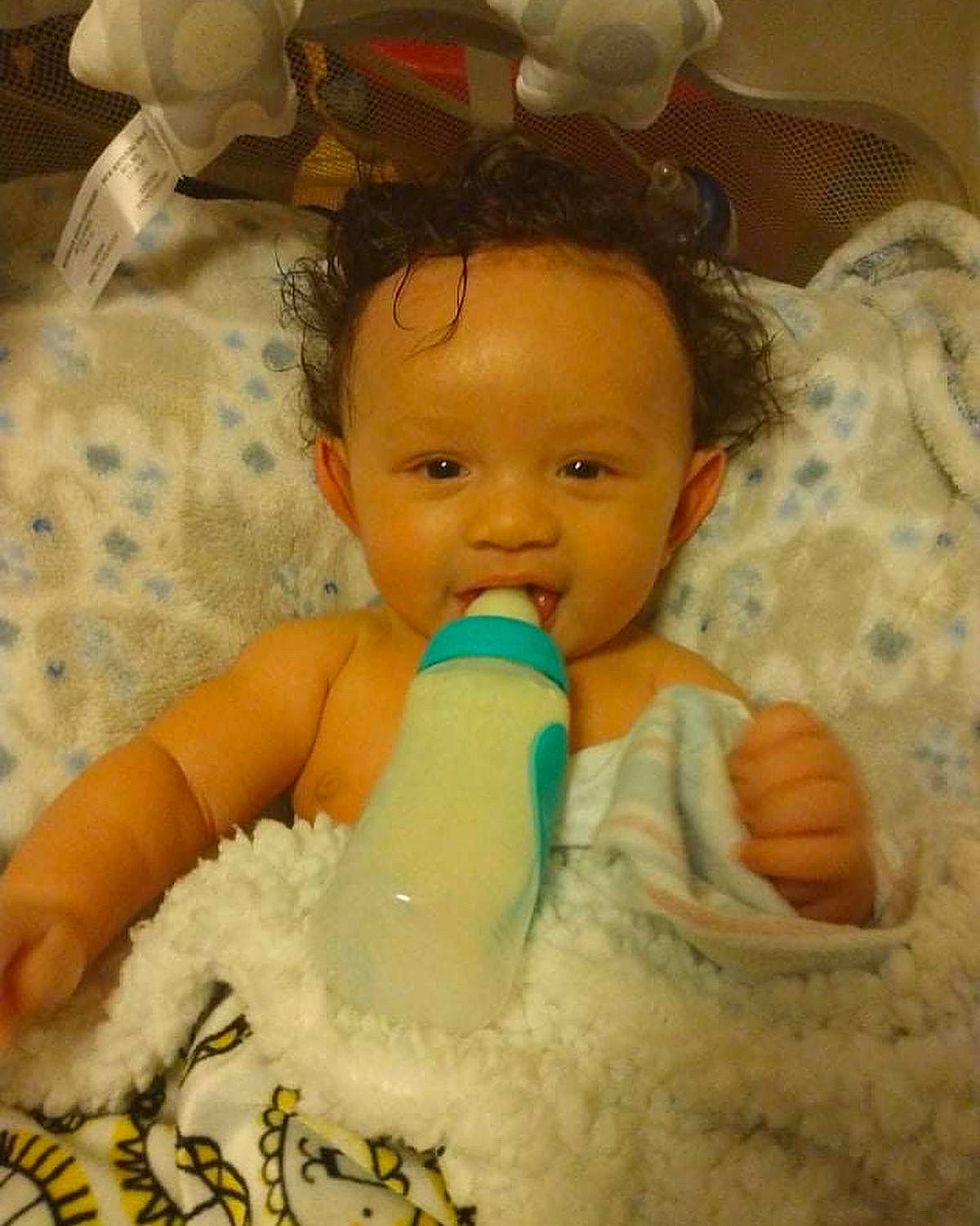 Kenzo is registered to the contest to win money with this photo: arm, baby, cheek, comfort, drinkware, ear, gesture, hand, happy, head, iris, mouth, nose, organ, person, plastic_bottle, product, skin, thumb, toddler