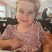 Julia participe au concours pour gagner de l'argent avec cette photo : background, casual, child, dining, face, floral_dress, furniture, hair, hand, happy, indoor, lens_flare, light, people, person, portrait, restaurant, seated, smile, table
