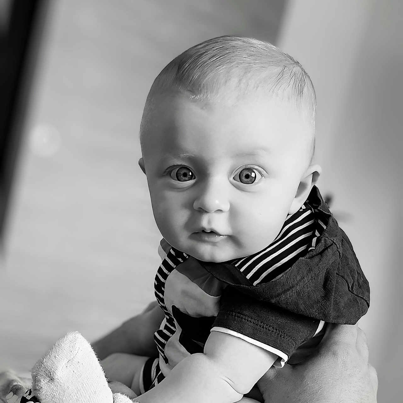 Liam participe au concours pour gagner de l'argent avec cette photo : baby, black_and_white, child, closeup, clothing, curious, cute, expression, eyes, face, hand, holding, indoors, infant, person, portrait, skin, socks, soft_light, striped_clothing